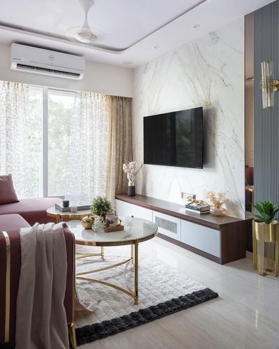 Living room with marble tv wall, wood console, rose sofa, and round marble coffee table