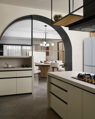 Kitchen with black arched glass partition opening to a round dining table beyond