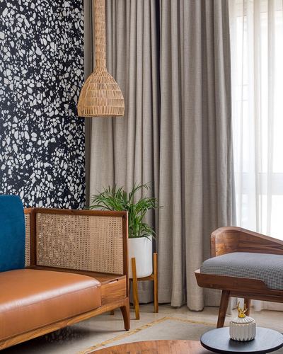 Living room corner with cane pendant light, terrazzo wall, leather-and-cane sofa and wooden bench