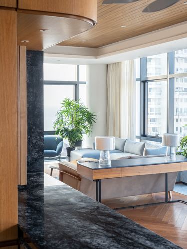 Living room with stone column, wood ceiling, city view through floor-to-ceiling windows
