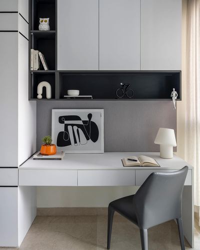 White floating study desk with black open shelving, grey chair and abstract art