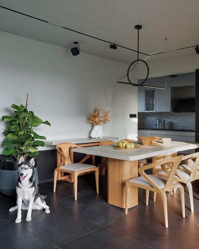 Dining area with wooden table, curved chairs, black pendant light, and husky dog on dark tiled floor