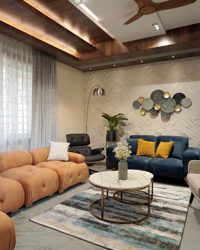 Living room with orange sofa, navy velvet sofa, round marble coffee table and wall disc art
