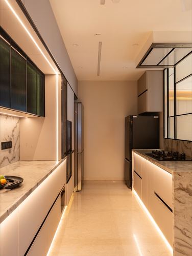 Galley kitchen with marble counters, glowing under-cabinet lighting, and black appliances