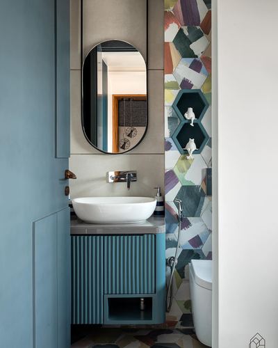 Teal fluted vanity with oval mirror beside patchwork hexagon tiled wall in small bathroom