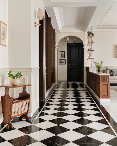 Long hallway with black and white checkerboard marble floor leading to an arched black door