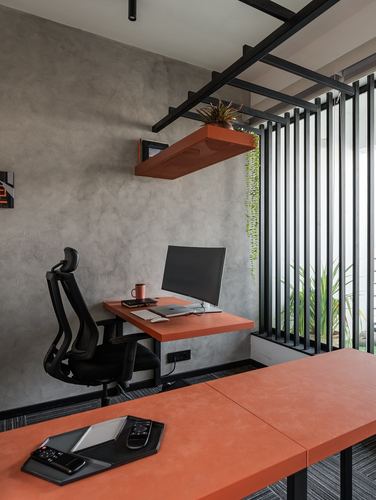 Home office with orange desk, black chair, and steel louvered wall by window