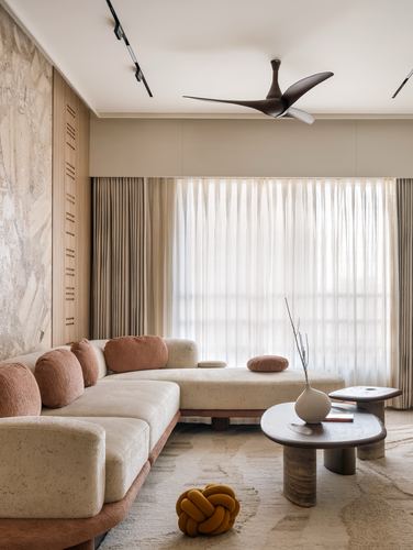 Beige living room with curved boucle sofa, stone accent wall, and sheer curtained window
