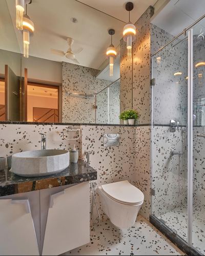Terrazzo-clad bathroom with vessel sink, wall-hung toilet, glass shower, and cluster pendant lights