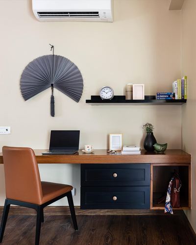 Wall-mounted study desk with laptop, orange leather chair, and floating shelf below an air conditioner