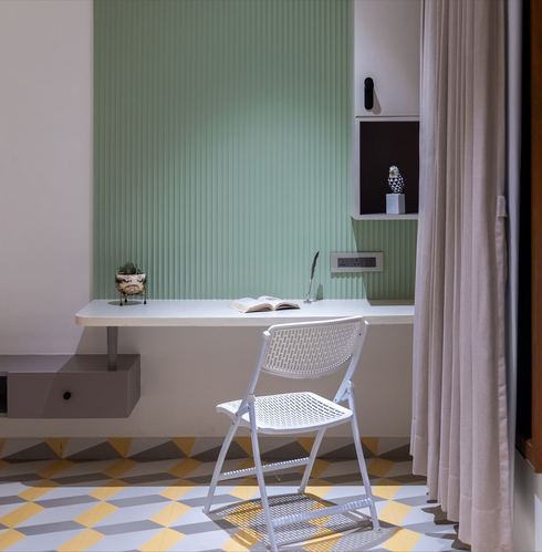 White wall-mounted desk against a fluted sage green wall with a patterned tile floor