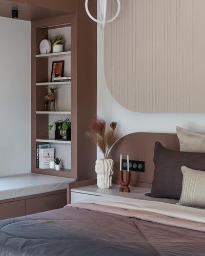 Bedroom corner with built-in shelving, curved fluted panel wall, and layered pillows on bed