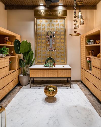 Symmetrical pooja room with gold deity panel, marble floor and patterned wood cabinetry