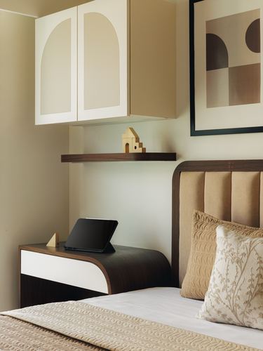 Bedroom corner with curved wall cabinet, floating shelf, nightstand and channel-tufted headboard in warm neutrals