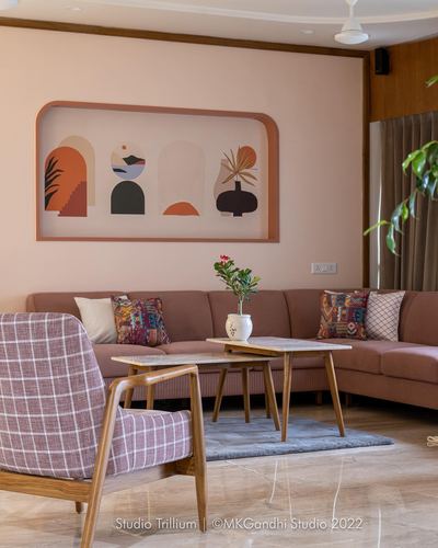 Living room with rose-toned sectional sofa, checkered armchair, and framed abstract art in recessed wall niche