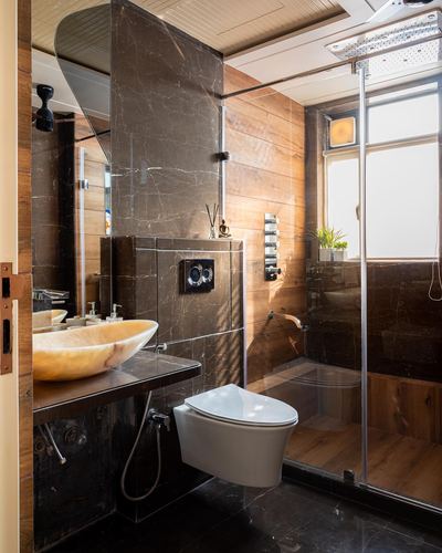 Bathroom with dark marble wall, wood-panel shower, vessel sink and wall-hung toilet