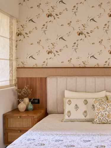 Bedroom corner with floral wallpaper, wood and cane nightstand, and ribbed beige headboard