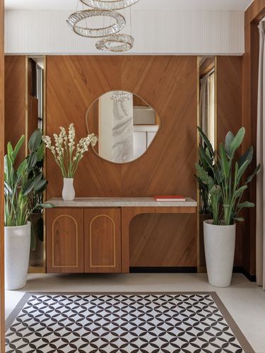 Wood-paneled foyer with round mirror, marble-top console, brass trim, and patterned floor tile