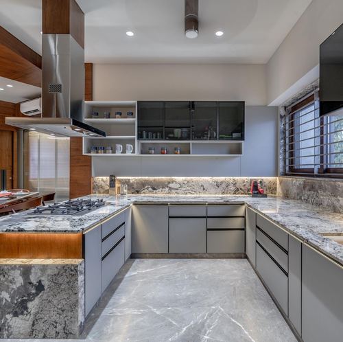 Modern U-shaped kitchen with grey stone island, wood accents, and stainless steel chimney hood