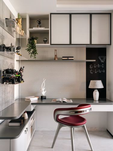 Study desk with red sculptural chair against perforated panel wall and chalkboard niche