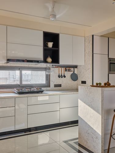 White gloss kitchen with marble-look backsplash, island counter and sunlight streaking across floor