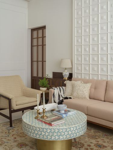 Living room with pink sofa, cane armchair, and round inlay coffee table on brass base