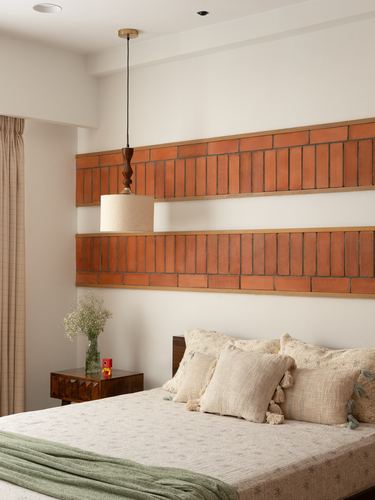 Bedroom with terracotta tile banded wall, wood bed, cane pendant light, beige linens with green throw