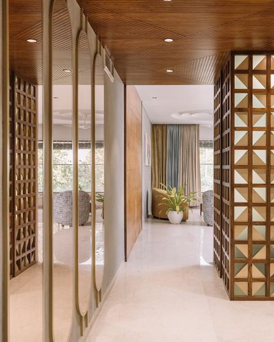 Wood-clad corridor with arched mirror panels and a triangular lattice screen leading to a seating area