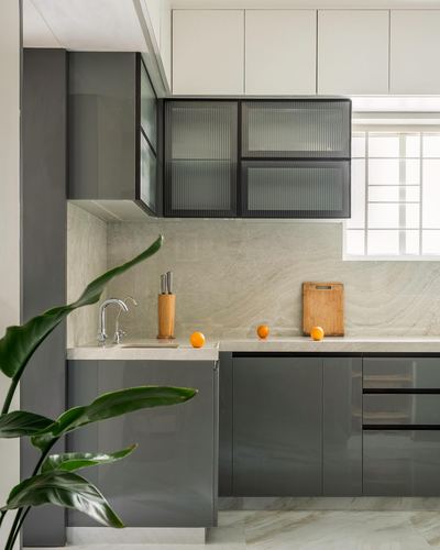 Modern kitchen with grey glossy cabinets, stone backsplash, and ribbed glass upper cabinet