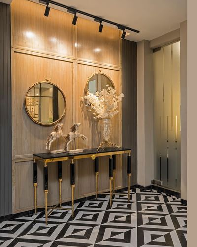 Entryway console with two round mirrors, brass-legged table, and black-and-white geometric floor tile