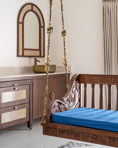 Carved wooden swing with blue cushion beside a cane-mirrored vanity unit