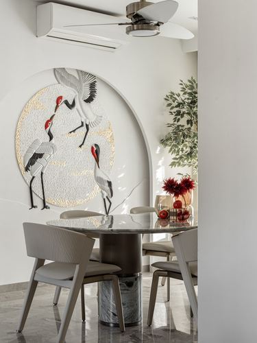 Round marble dining table with grey chairs beneath arched crane wall art panel