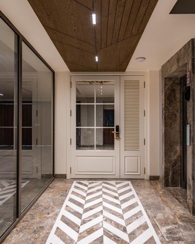 Entrance foyer with wood-panelled ceiling, glass-paned door, and chevron marble floor pattern