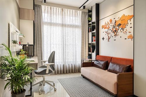 Study nook with desk and chair beside a sofa under a wooden world map wall art