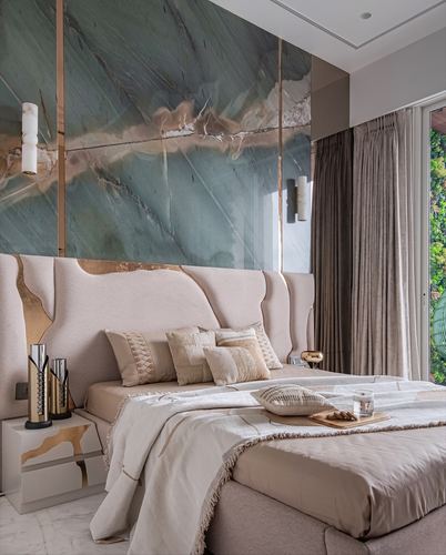 Bedroom with green-veined stone feature wall above a curved upholstered headboard and beige linens