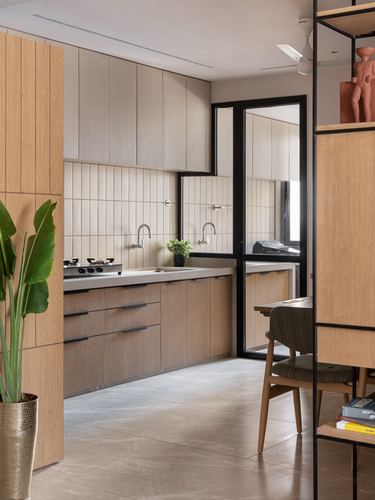 Wooden kitchen with ribbed tile backsplash, wall-mounted taps, and black steel glass partition