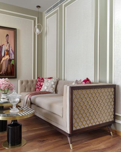 Beige tufted sofa with gold lattice side panel in a paneled olive living room