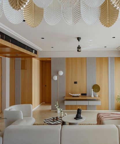 Beige living room with fluted wood paneling, floating console, and scalloped ceiling installation