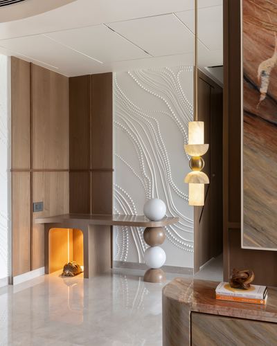 Foyer with textured white wall panel, wooden console, glowing niche, and sculptural pendant lamp