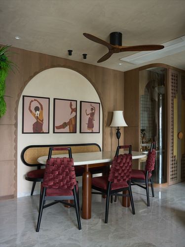 Dining nook with oval marble table, maroon velvet chairs, cane bench inside an arched niche with dancer artworks