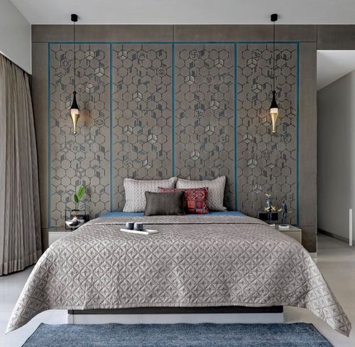Grey bedroom with large hexagon-patterned panel wall behind bed and two pendant lights