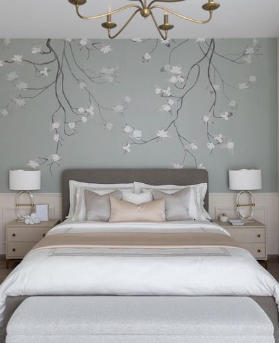 Bedroom with grey upholstered headboard beneath a sage floral mural, flanked by lamps and nightstands.