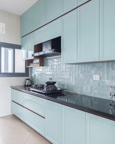 Mint green shaker kitchen with black countertop and herringbone tile backsplash