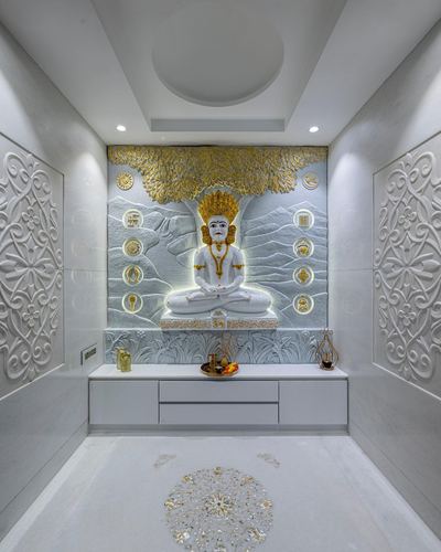 Symmetrical white marble pooja room with backlit carved deity relief and gold accents