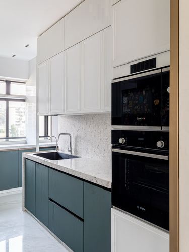Galley kitchen with white upper cabinets, teal lower cabinets, stone counter, and built-in black Bosch oven