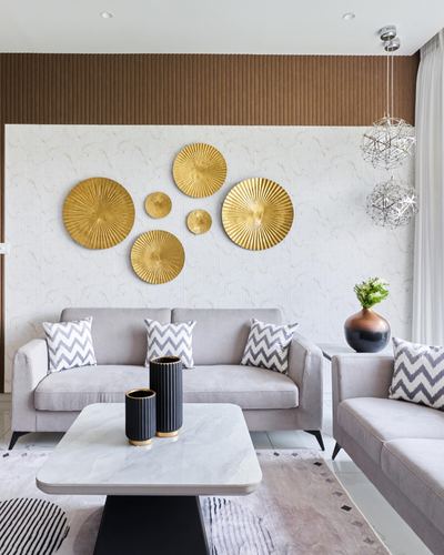 Grey sofas face marble coffee table beneath gold sunburst wall discs and fluted wood paneling