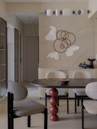 Beige dining room with sculptural wall art, oval dark table on spherical base, and upholstered chairs