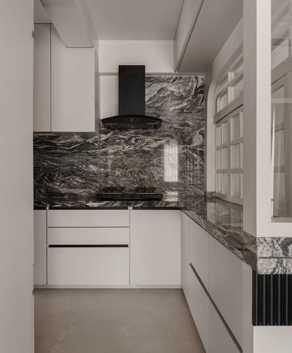 L-shaped kitchen with veined stone backsplash, black hood, and curved arched window in corner