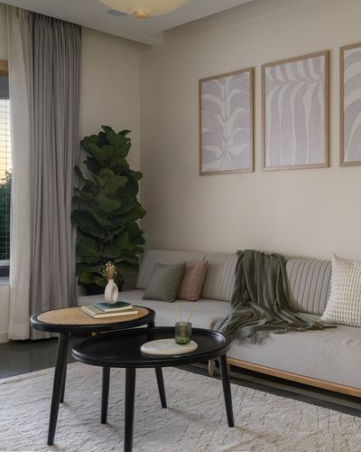Neutral living room with channel-tufted sofa, cane nesting tables and fiddle leaf plant