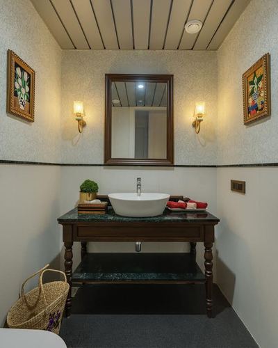 Bathroom with antique wooden vanity, green stone top, vessel sink, mirror and wall sconces
